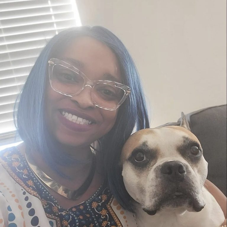 You Can Leave Pet Sitting Services - North Austin, Texas Smiling person with blue hair and glasses, holding a dog with a white and brown coat.
